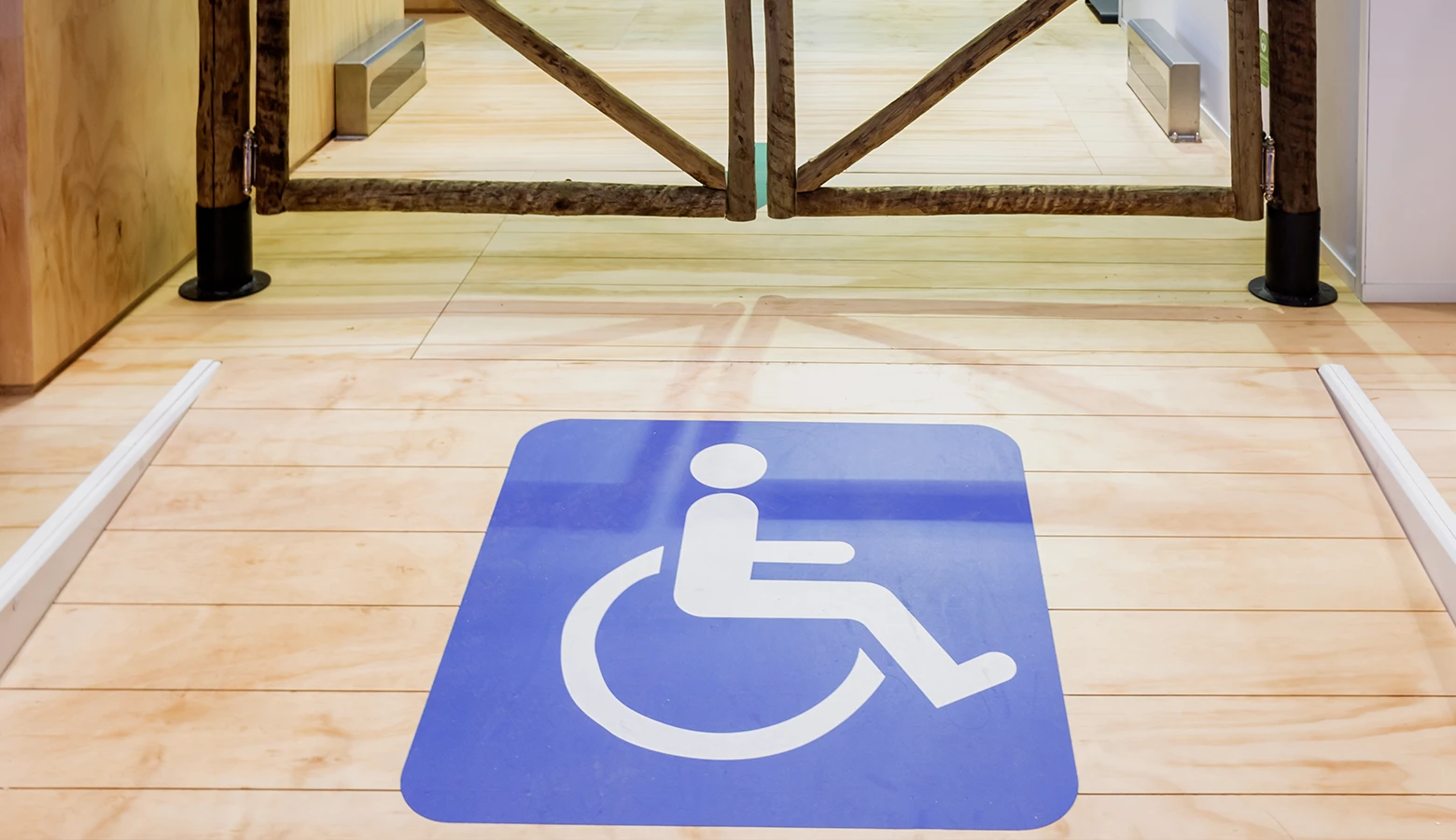 An international wheelchair symbol placed on a wooden floor in a room, indicating accessibility for individuals with disabilities.